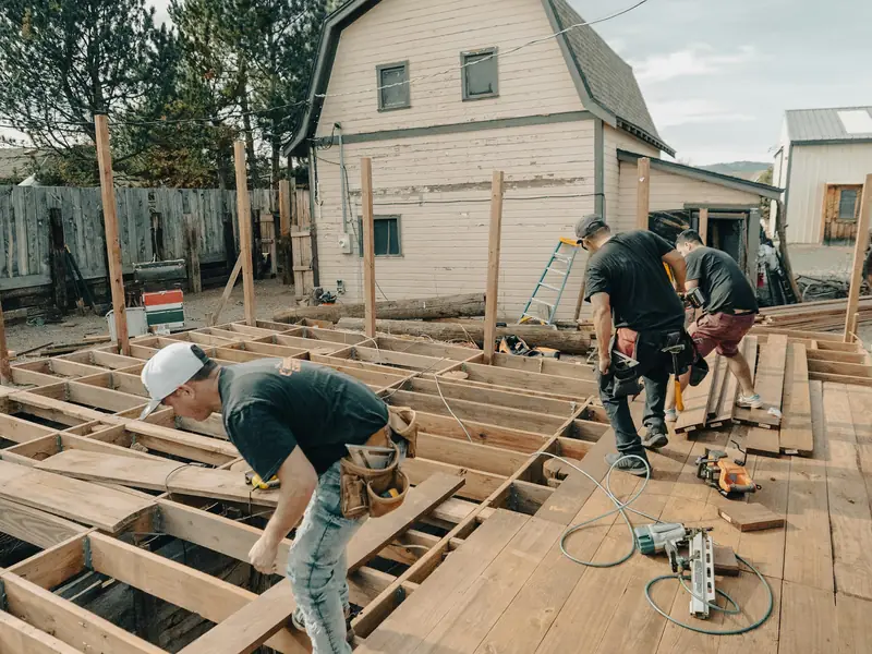 Handwerker bauen gemeinsam die Unterkonstruktion einer Holzterrasse